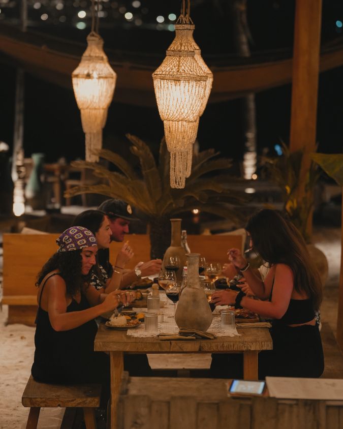 Guests enjoying a candlelit dinner under hanging lanterns at BAHIA, a popular beachfront barbecue restaurant on Gili Air.