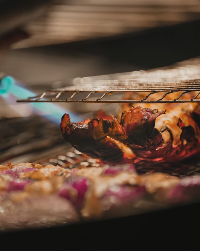 A close-up of a whole lobster being freshly grilled over open flames at a top barbecue restaurant on Gili Air.